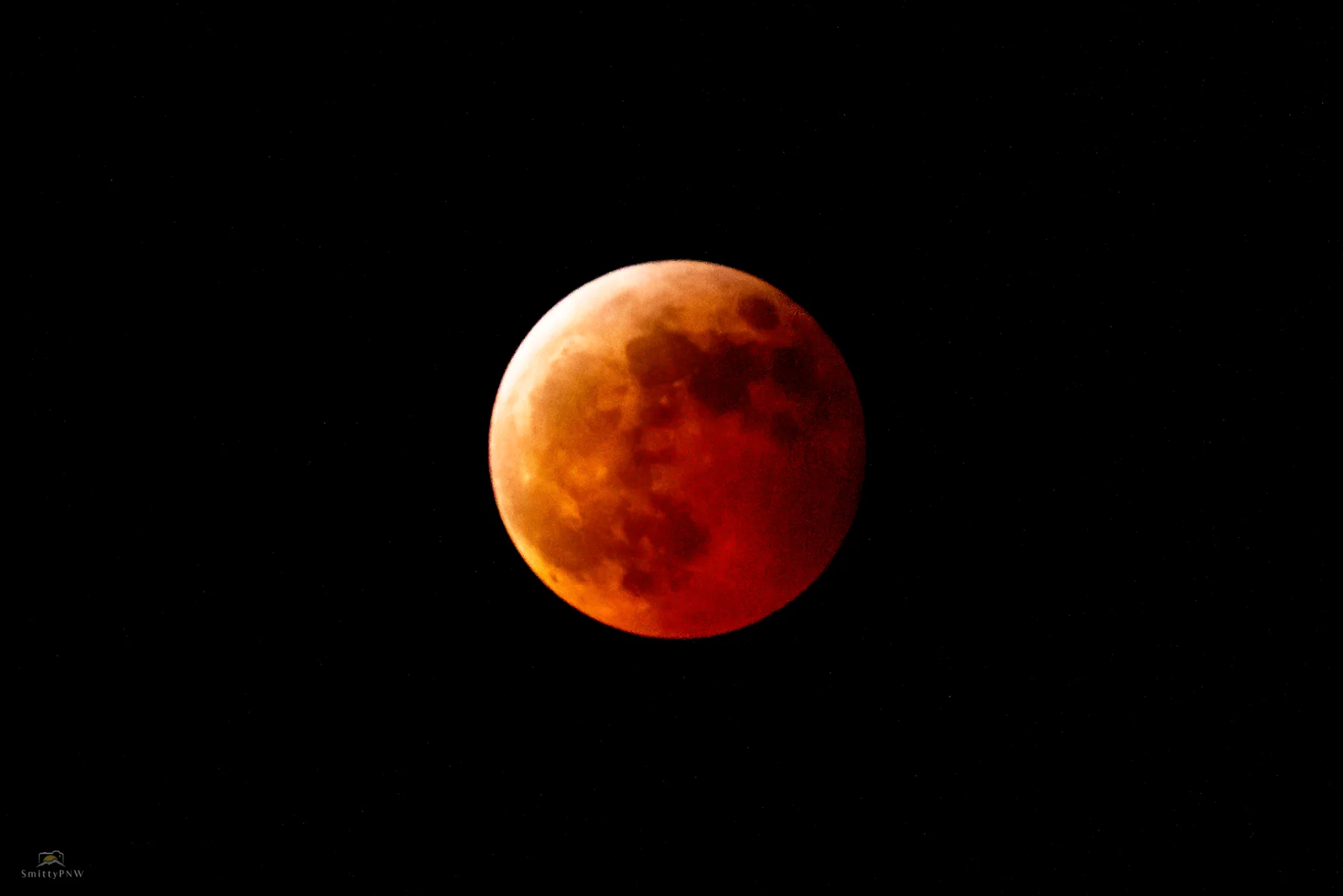 Deep red total lunar eclipse against a black sky