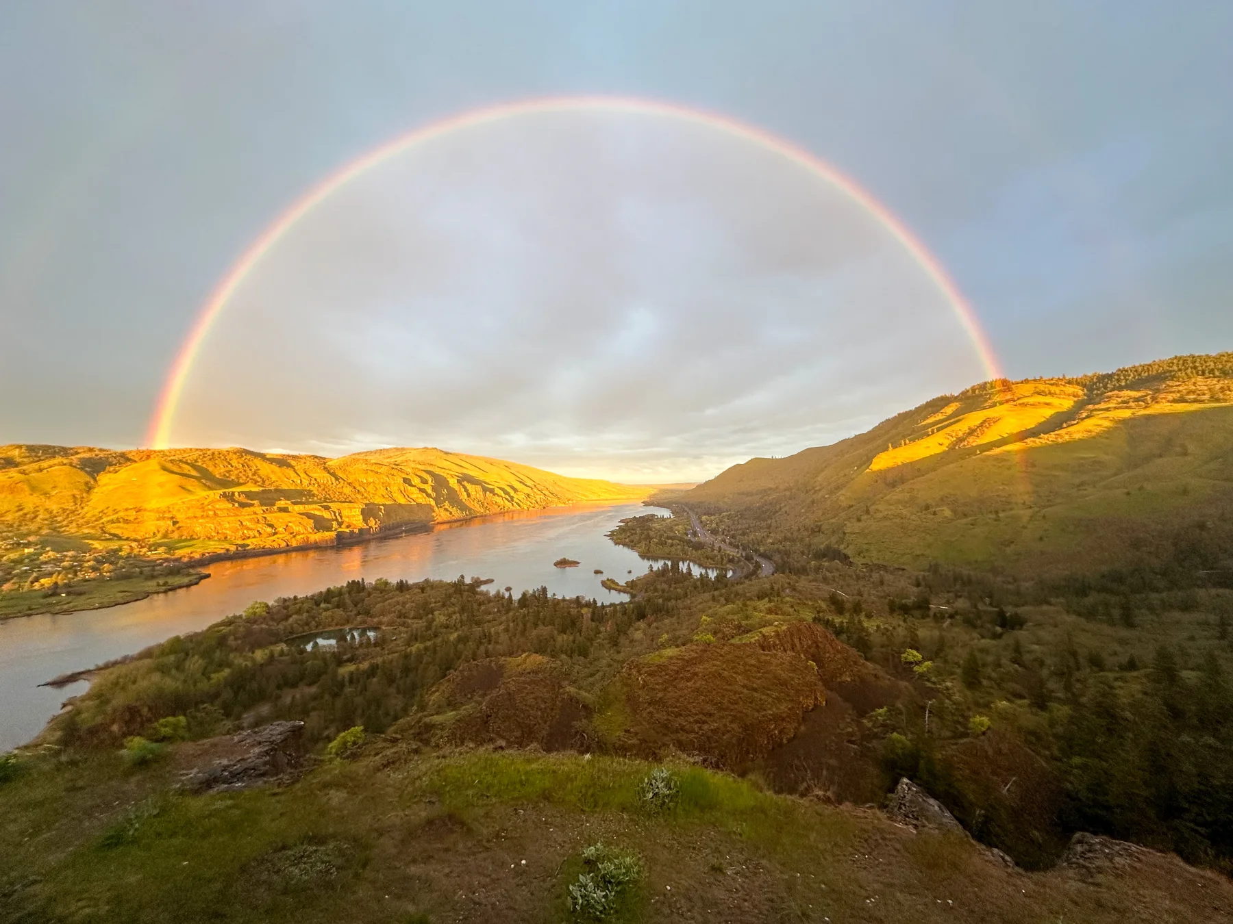 Full rainbow arcing over the Columbia River Gorge at sunset
