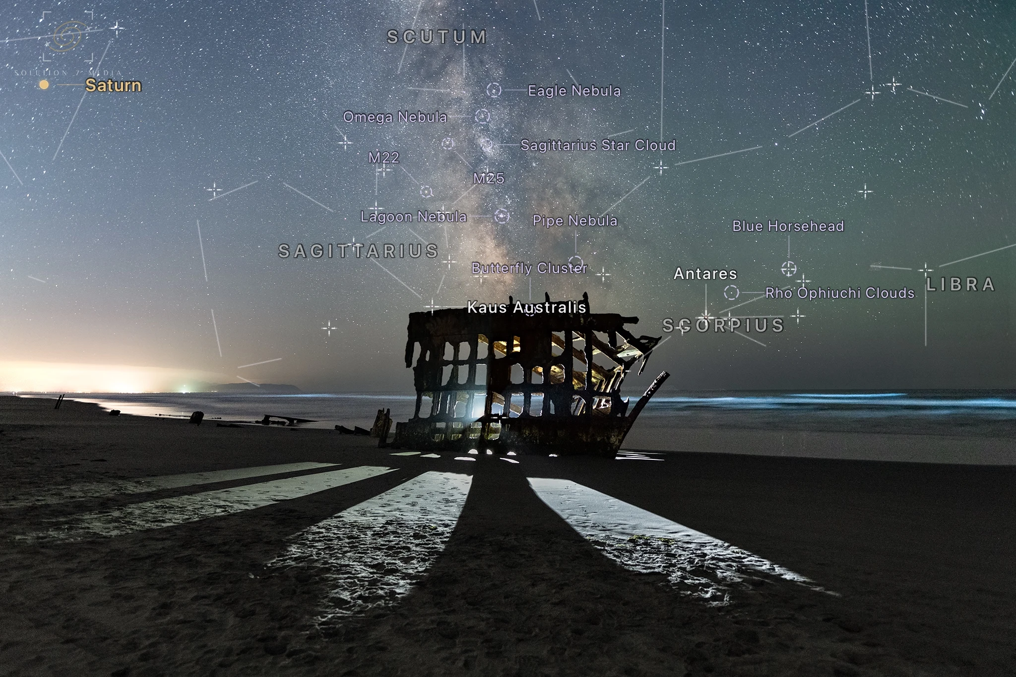 Night Atlas constellation, planet, star, and deep-sky labels over the Milky Way and a Pacific coast shipwreck