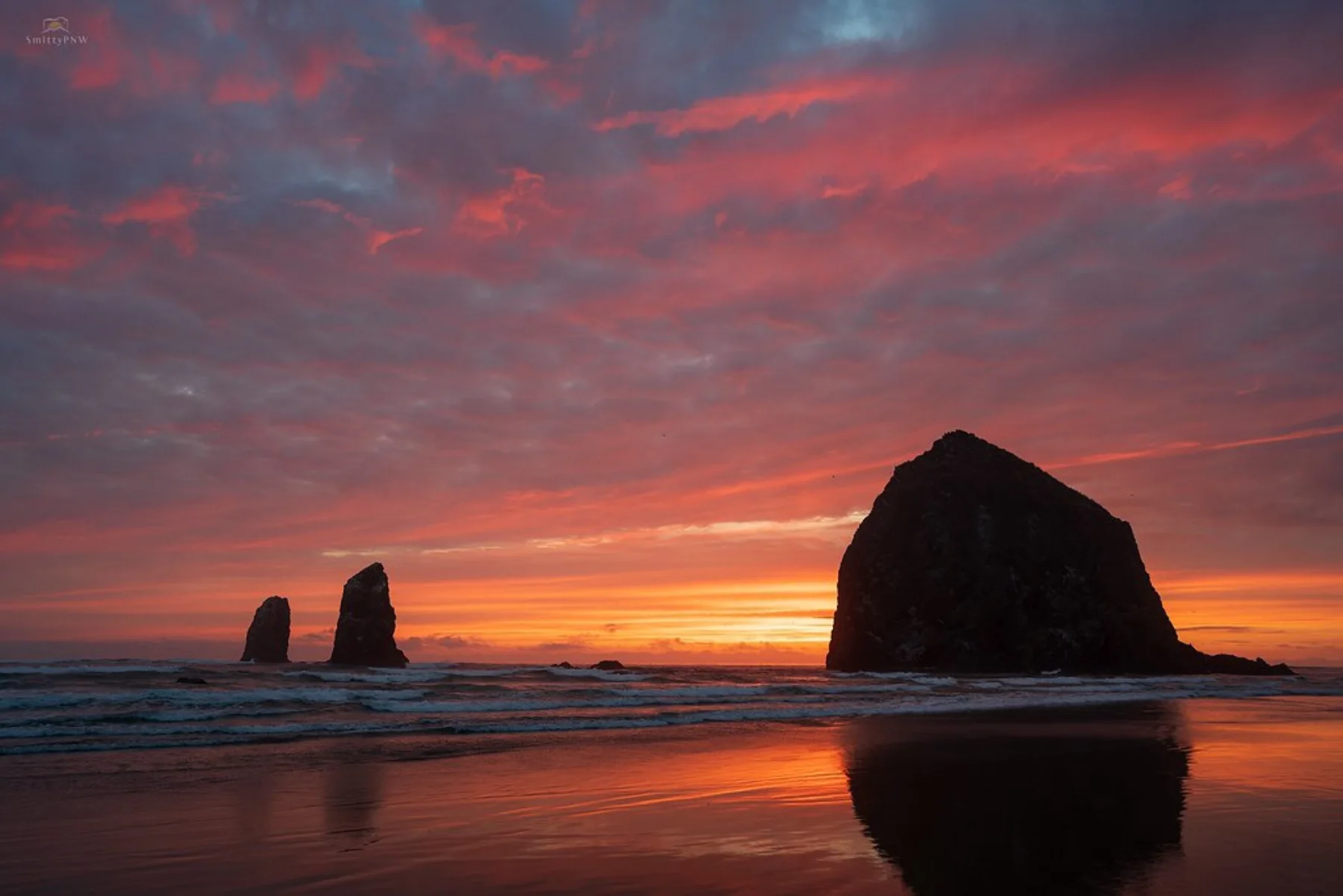 A vivid Pacific coast sunset behind Haystack Rock